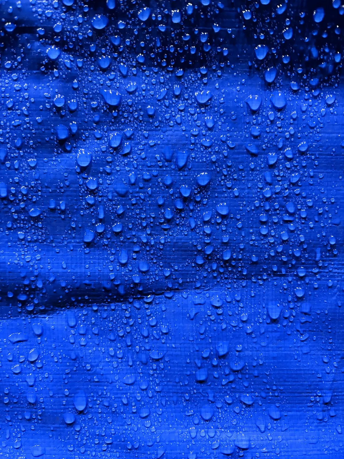 Капли воды на синей мембранной ткани
